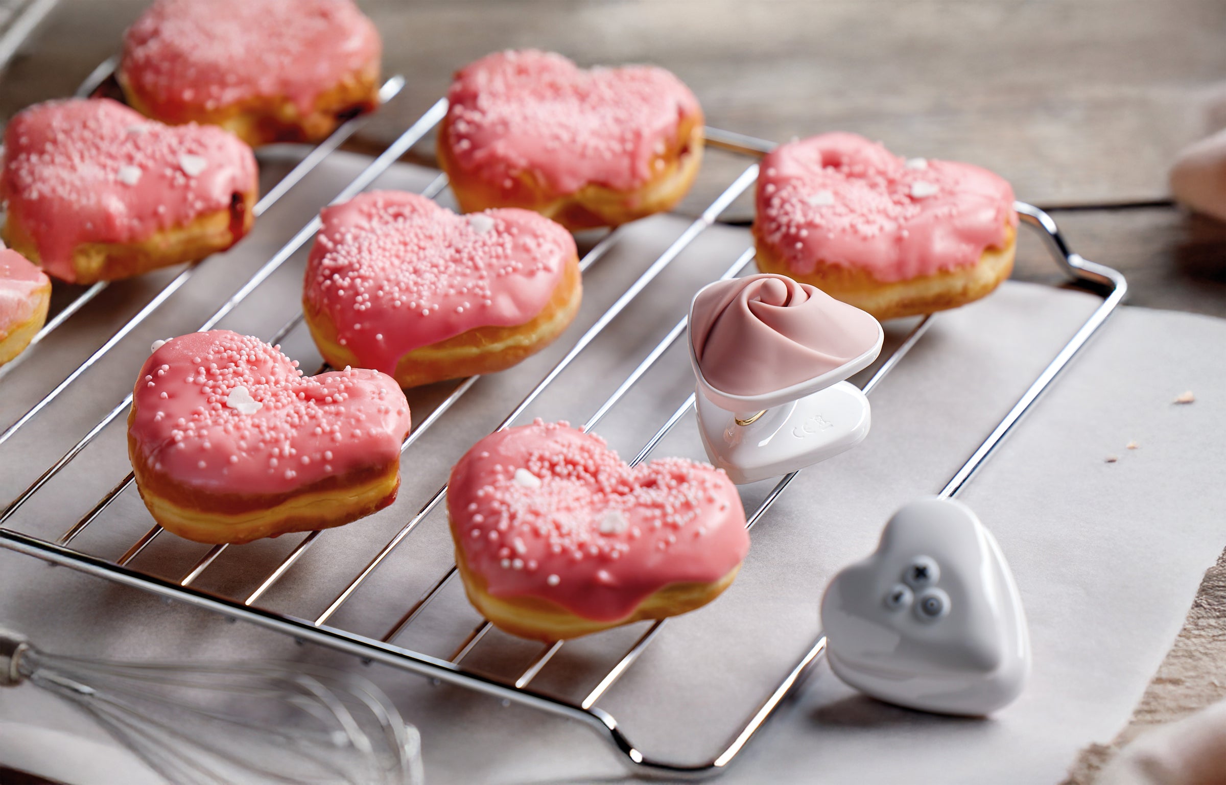 Promo Mystim Auflegevibrator Heart's Desire mit Herz Donuts auf einem Backblech Gitter