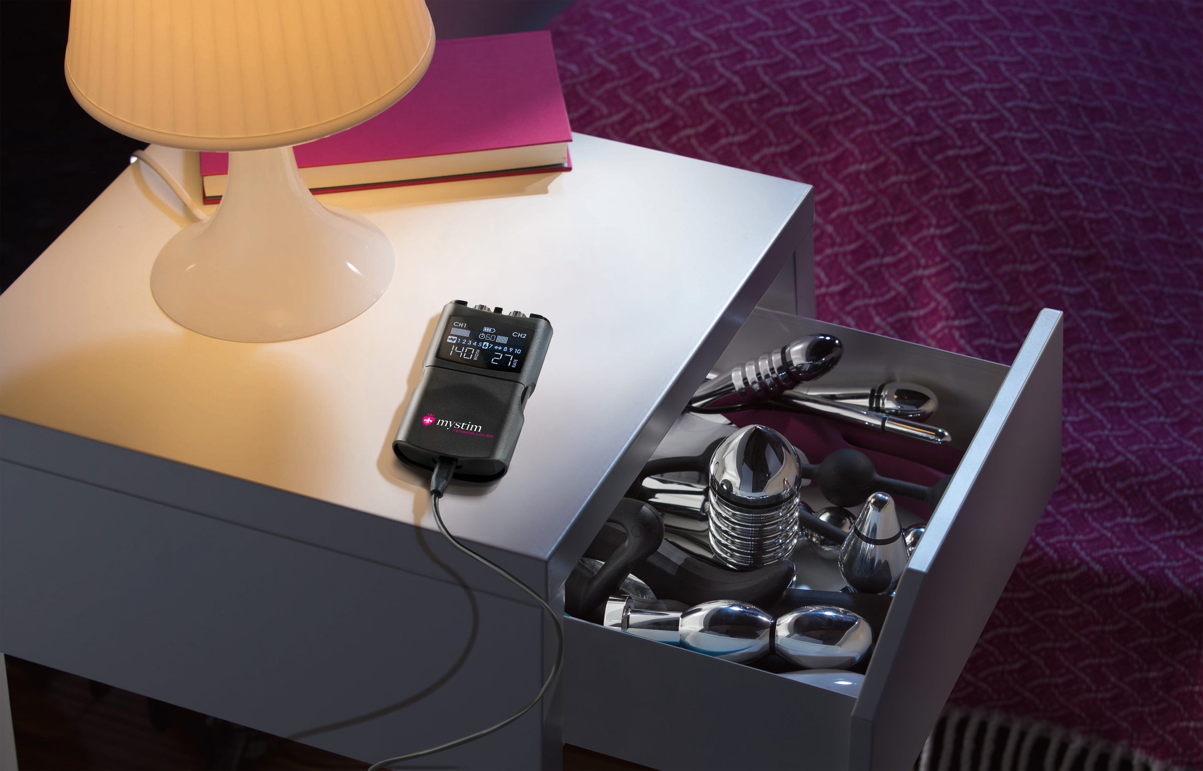 Promo Tension Lover 2 Powerbox zur Elektrostimulation auf Nachttisch mit E-Stim Toys in der Schublade