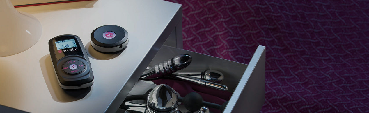 Kategorie Header Mystim Powerboxen Cluster Buster Sultry Sub auf Nachttisch mit Dildos in der Schublade